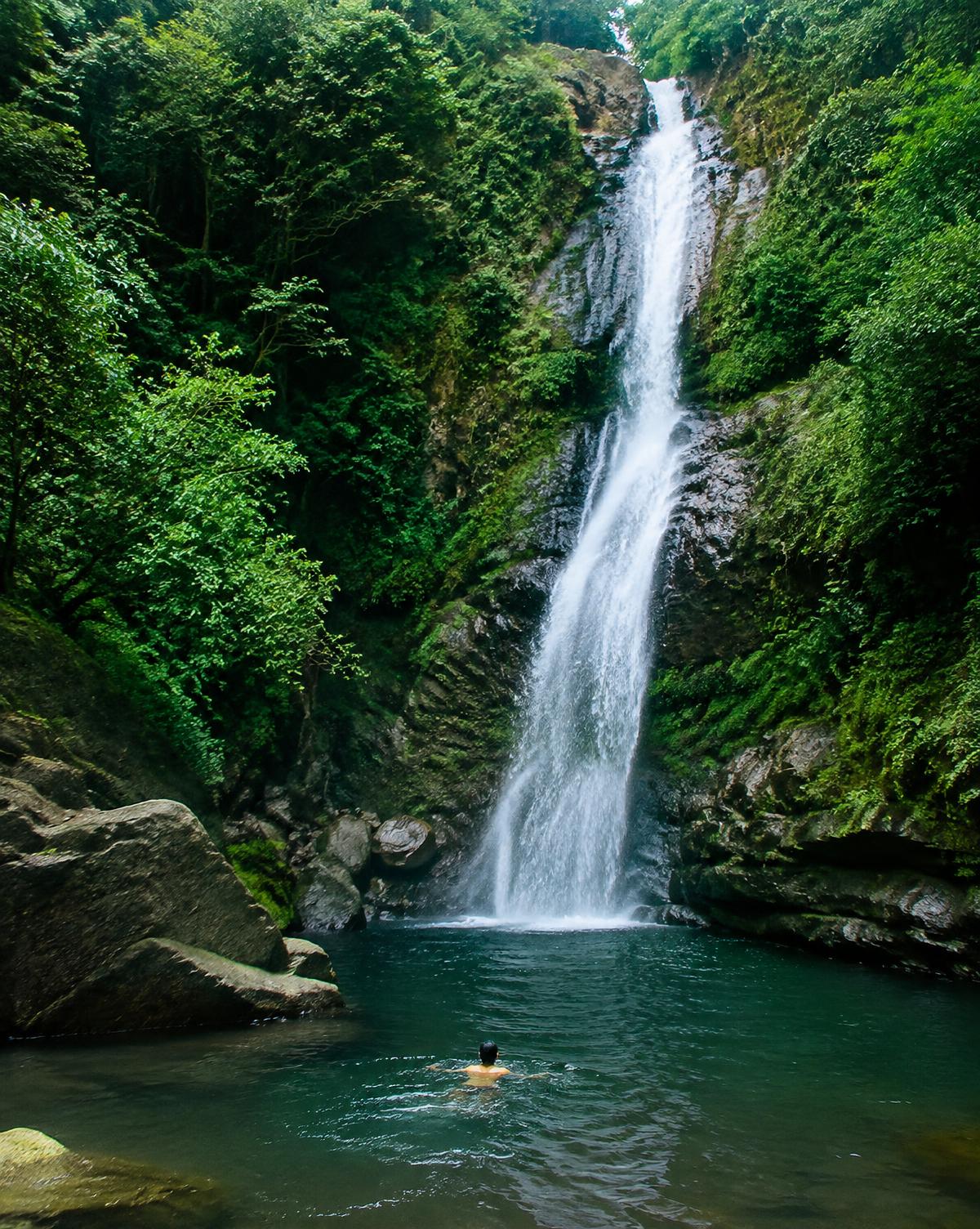 Swimming beneath a jungle waterfall